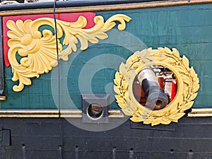 Old naval cannon in the round hole of wooden sailing ship