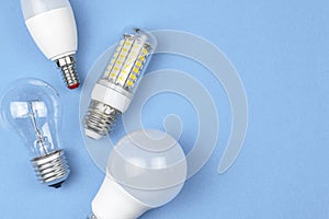 Old and new bulbs together, pastel blue background. Energy saving concept. Flat lay, top view photo