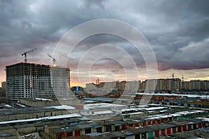 Old and new city against the cloudy sky. View from the window of a new house on the area under construction. Evening in the