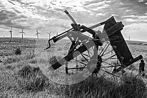 Old and new technology - wind turbines and abandoned plough - black and white