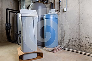 Old and new water softener tanks in a utility room