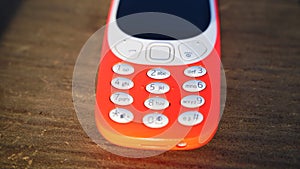 Old nokia 3310 keypad phone isolated on wooden table background. Old Classic mobile cell phone with small screen. Nokia branded