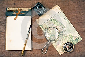 Old notebook, compass, map, pen and inkwell, magnifying glass on wooden background