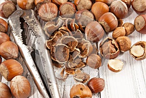Old nutcracker and hazelnuts on white wooden background