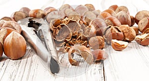 Old nutcracker and hazelnuts on white wooden background