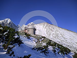 Stará hvezdáreň vysoko v horách, zasnežené štíty Vysokých Tatier na Slovensku