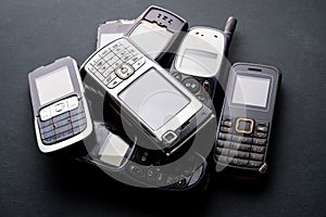 Old and obsoleted cellphones on black background