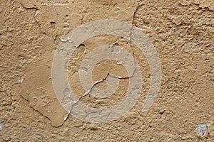 Old ochre painted stucco wall with cracked plaster. Background t