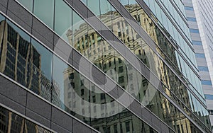 Old office buildings reflected in the glass of a modern office building