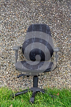 An old office chair in front of a stone wall photo