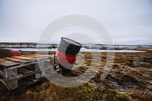 Old oil barrel in a field covered in the grass surrounded by a lake under a cloudy sky in Iceland