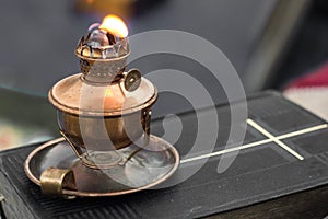 Real old oil lamp on a bible blurry background