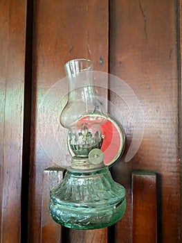 An old oil lamp made of glass hangs on a wooden wall