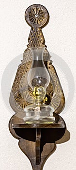 Old oil lamp powered by kerosene hanging on the wall. Isolated white background