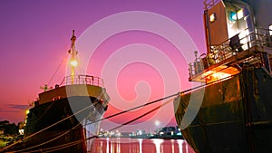 The old oil tanker ships moored in shipyard area at harbor during maintenance work against colorful twilight sky background