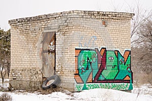 Old one-story brick building a rusty door with graffiti on wall