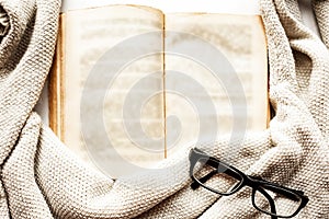 Old open book, glasses and sweater