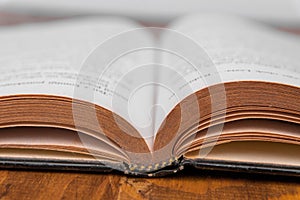 Old open book on a wooden table. White background. closeup