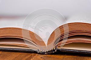 Old open book on a wooden table. White background. closeup