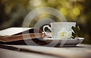 Old open books and a cup with a white wild rose