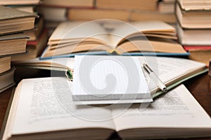 Old open books and notepad on the table. Piles of of books on reading desk in school study class room