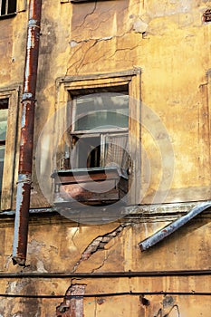 An old open window with a curtain and a wooden box on the windowsill in an abandoned apartment building. close up.