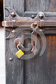 Old open wooden door carved forged deadbolt open attachments modern yellow padlock photo