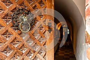 Old open wooden door with carved pattern and metal knob in a medieval castle