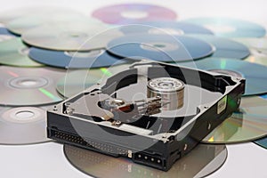 Old opened hard disc on a pile of compact discs