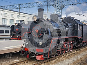 Old operating black steam locomotives with red stars at the passenger platforms