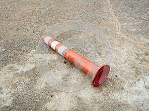 Old orange bollard was hit by car lay down on the concrete road