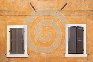Old orange house facade, closed brown window shutters in popular touristic historic village Garda