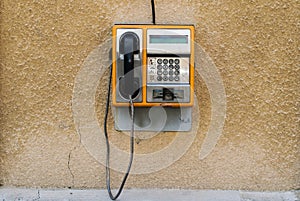 An old orange phone with a card. Street phone on a wall. This phone was used in Europe in the 1990s