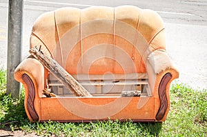 Old orange sofa thrown in the garbage from home on the street