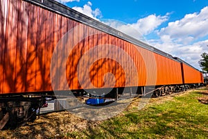 Old orange steal railroad car on tracks with a rusted bottom.