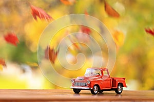 Old orange truck surounded by falling leaves