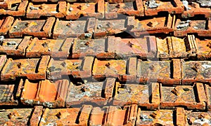 Old orange weathered roof shingles. Dirty stained ceramic tiles