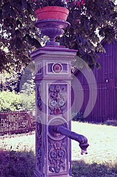 Old ornate cast iron village fountain with flower pot