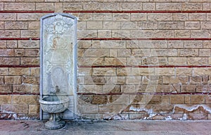 Old, ornate, embossed white marble fountain on a historical wall