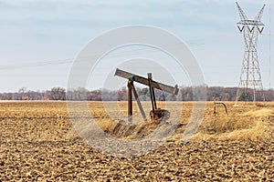 Old, orphaned oil well pump in farm field