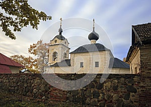 Old Orthodox church behind natural stone wall against background of the northern autumn sky
