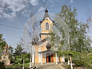 Old orthodox church of yellow color. White birch trees. Blue sky with olaks. Tsypovo. Moldova.