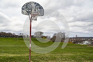 Old outdoor baskeball hoop with the broken wooden backboard in a park in Portland Maine.