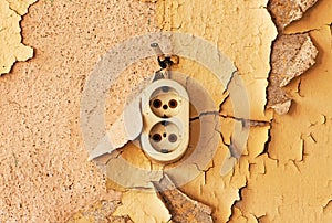 Old outlet and cable on a decrepit wall