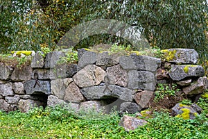 Old overgrown rock wall with forged loops as reinforcement