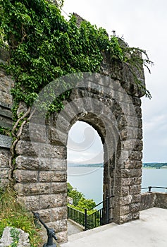 Old overgrown stone castle gate with a lake behind