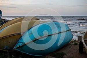 old overturned fishing boats on the seashore during sunset on the background of the sea