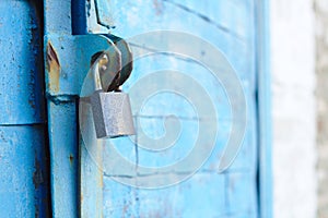 old padlock on a blue metal door with wooden planks cracked paint and rust