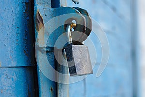 old padlock on a blue metal door with wooden planks cracked paint and rust