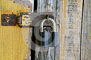 Old padlock hanging on a wooden shabby door